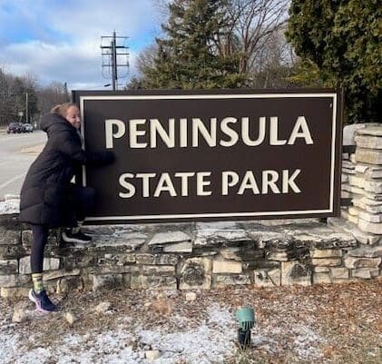 A Julie's staff member hugs the Peninsula State Park sign